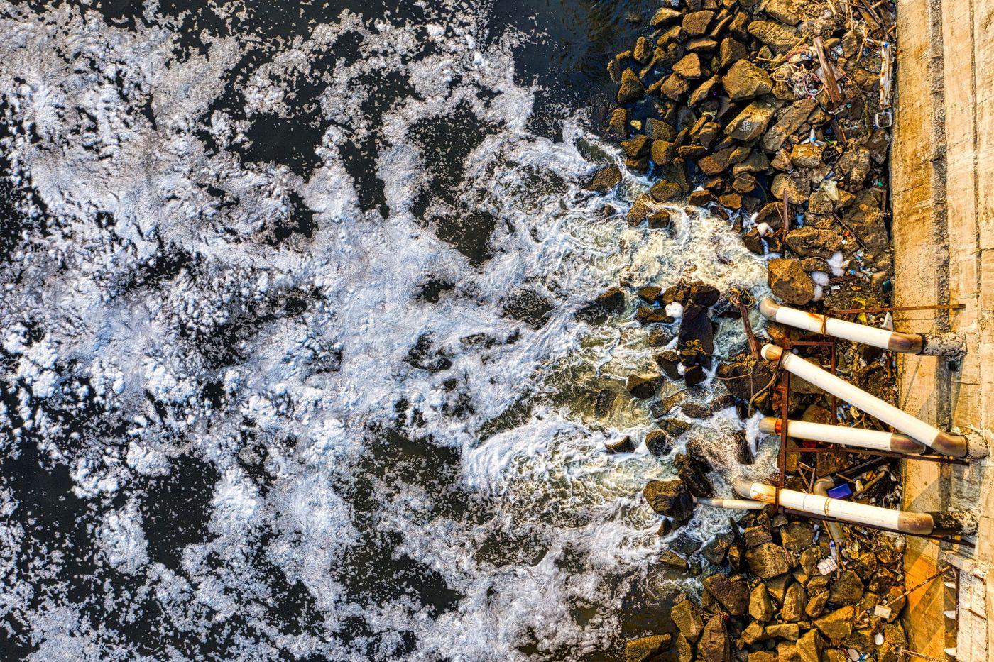 Discoloured water discharging into the sea beside a rocky breakwater
